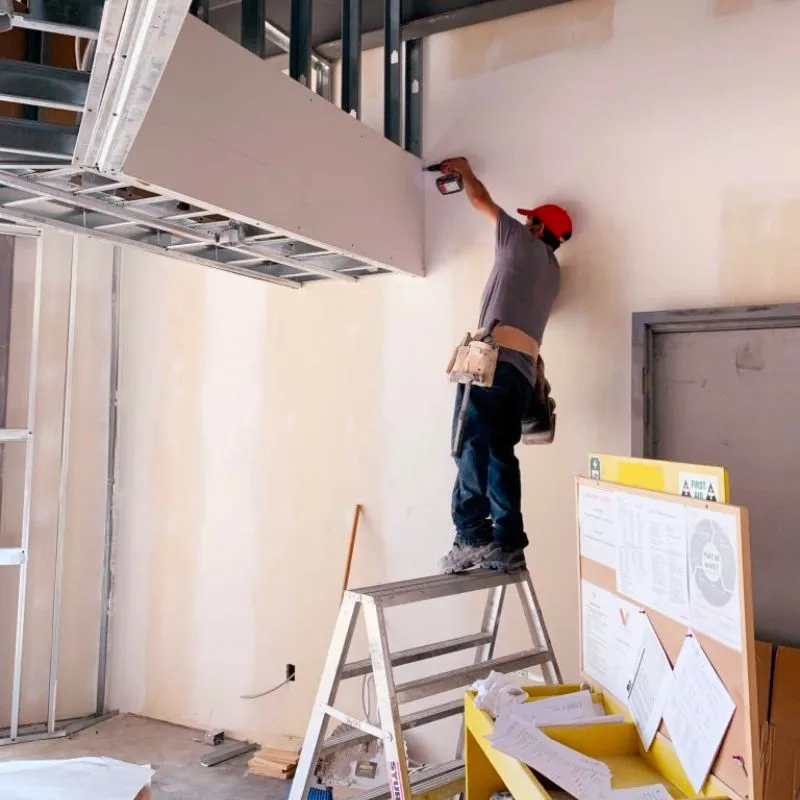 a drywall contractor in edmonton installing a drywall sheet onto a steel frame